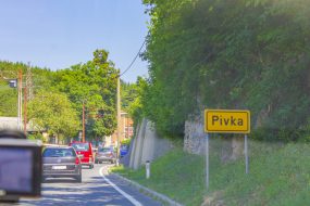 Yellow place-name sign and road to Postojna Pivka in Slovenia.