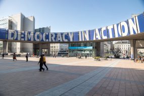 People walking in front of the european parliament with democracy in action sign in brussels