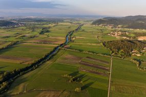 Aerial view of river bending across fields at sunset. Ljubljanica running through marshes, Slovenia.